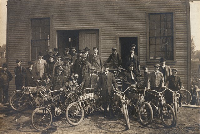 Harley-Davidson employees outside the 1906 Chestnut Street factory in Milwaukee, each holding a motorcycle