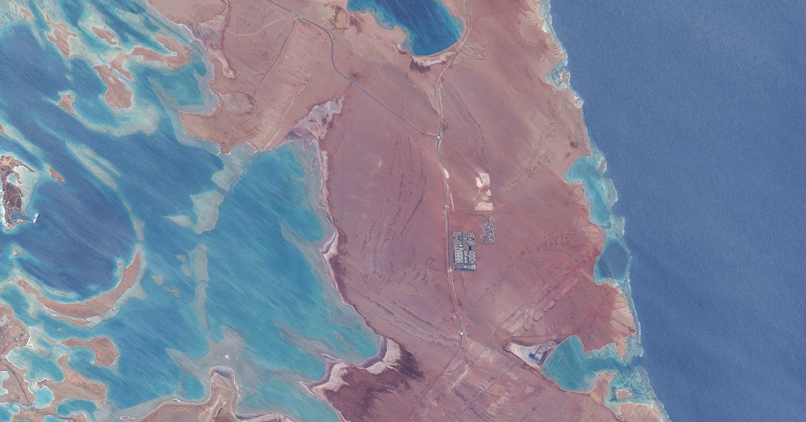 NASA ISS astronaut photograph of the Gulf of Aqaba coastline near NEOM, showing the Neom Residential Camp, roads and turquoise reef lagoons along the Red Sea