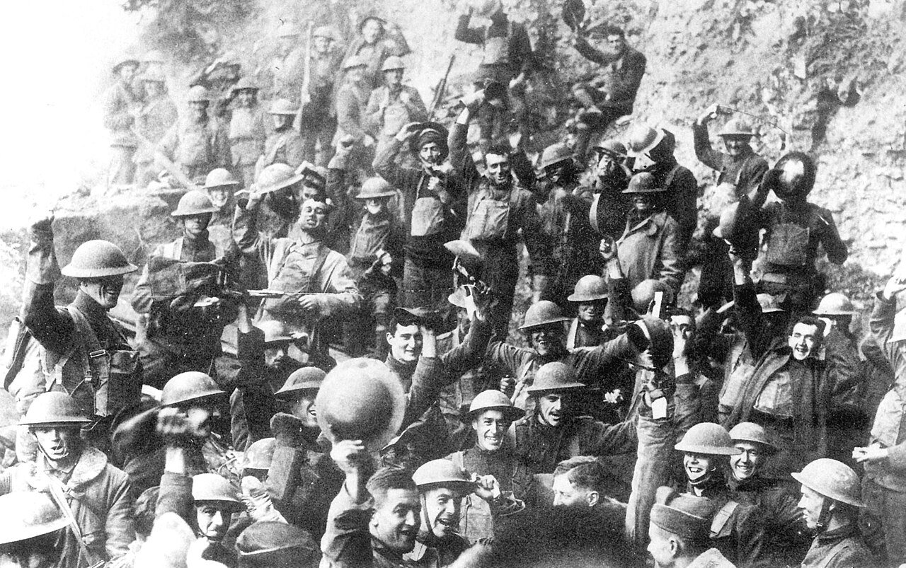 Men of the US 64th Regiment, 7th Division, cheering and waving helmets as they celebrate news of the Armistice on 11 November 1918