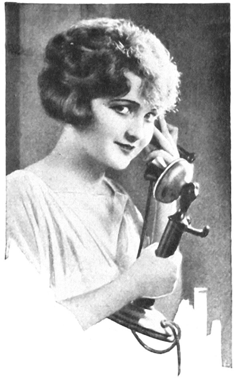 A woman holding a candlestick telephone, 1923