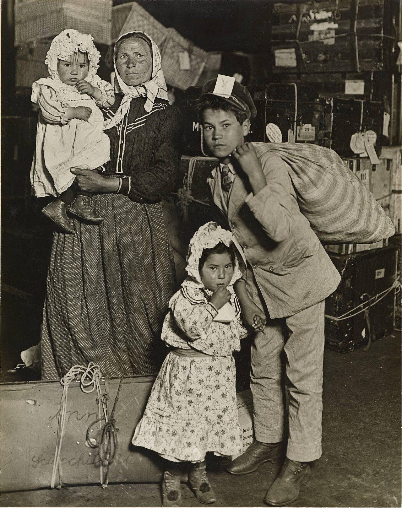 Immigrant mother and three children in the baggage room at Ellis Island, 1905, photographed by Lewis Hine