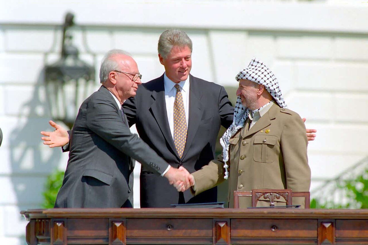 Yitzhak Rabin and Yasser Arafat shake hands with Bill Clinton at the White House on 13 September 1993, the day the Oslo Declaration of Principles was signed