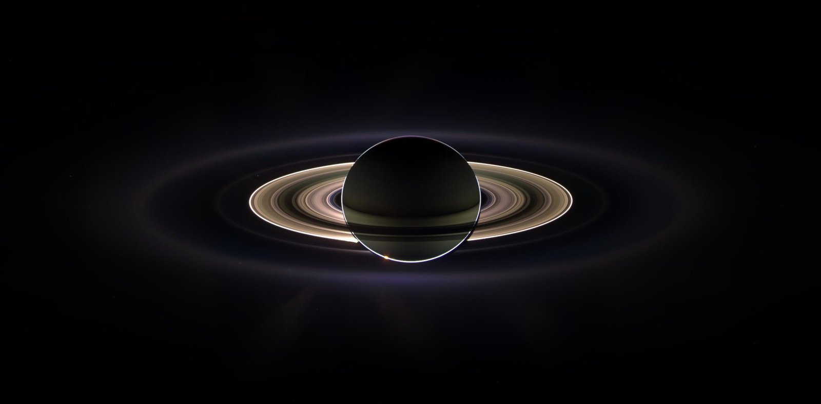 Saturn backlit by the Sun, rings glowing, photographed by the Cassini spacecraft