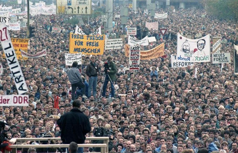 Dense crowd at the Alexanderplatz demonstration in East Berlin with banners reading Freie Presse fuer freie Menschen and Neues Forum