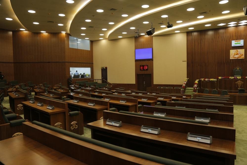 Interior of the Andhra Pradesh Legislative Assembly chamber with rows of wooden desks
