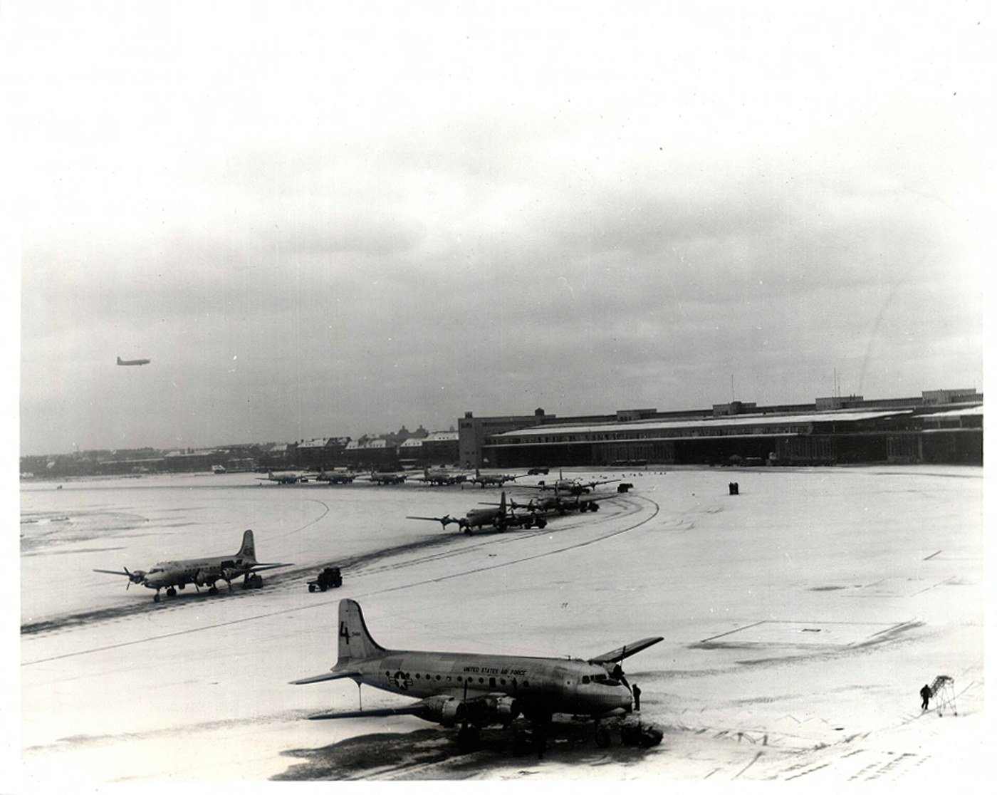 C-54 Skymaster aircraft parked in snow on the Tempelhof apron with the curved terminal in the background