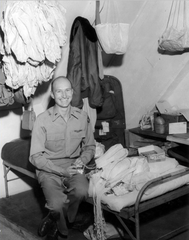 Lieutenant Gail Halvorsen seated beside handkerchief parachutes with candy tied to them