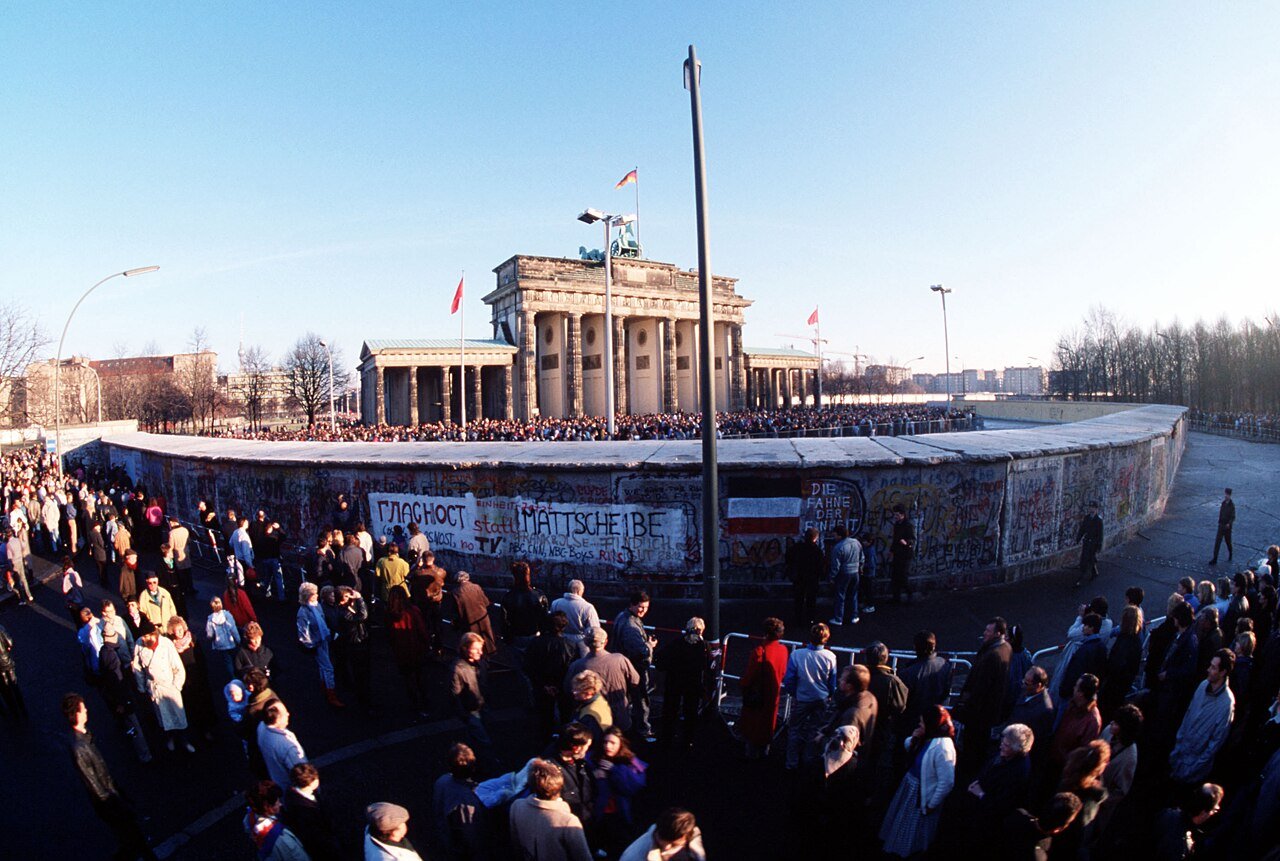 The Brandenburg Gate behind the graffiti-covered Wall with a crowd gathered in front, 1 December 1989