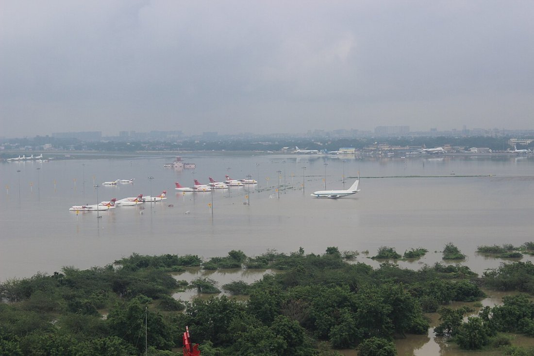 Aircraft standing in floodwater at Chennai airport with tree-lined flooded ground in the foreground