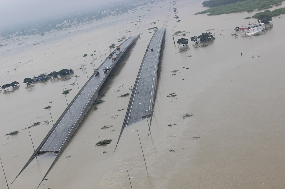 Aerial view of two flooded bridges stretching across a wide sheet of brown floodwater in Chennai