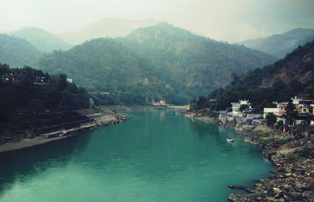 The Ganges flowing past hills and riverside buildings at Rishikesh in Uttarakhand