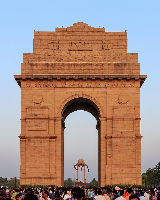 India Gate in New Delhi at dusk with visitors gathered below the arch