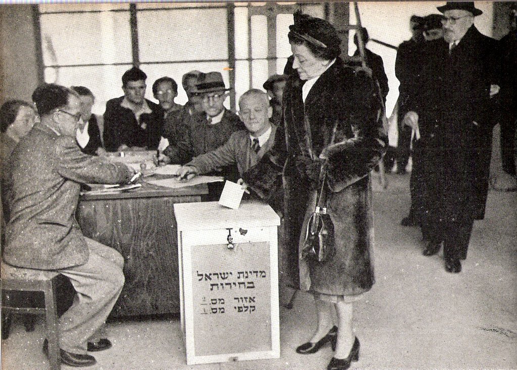 Black-and-white photo of Vera Weizmann placing a ballot in a wooden ballot box at Israel's first Knesset election in January 1949