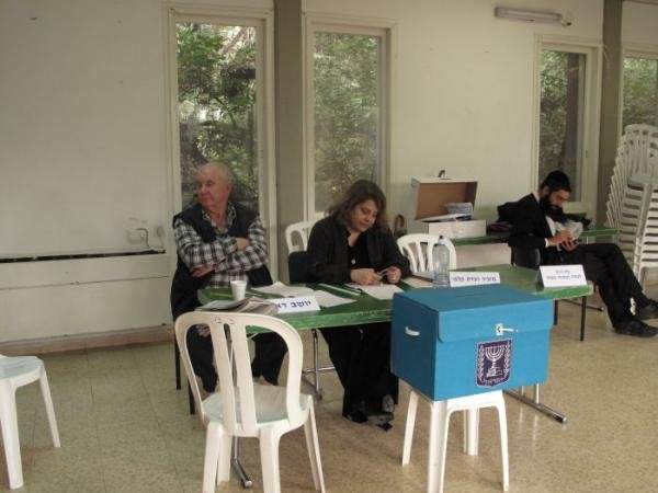Polling-station committee members seated beside a blue Israeli ballot box during the 2009 Knesset election