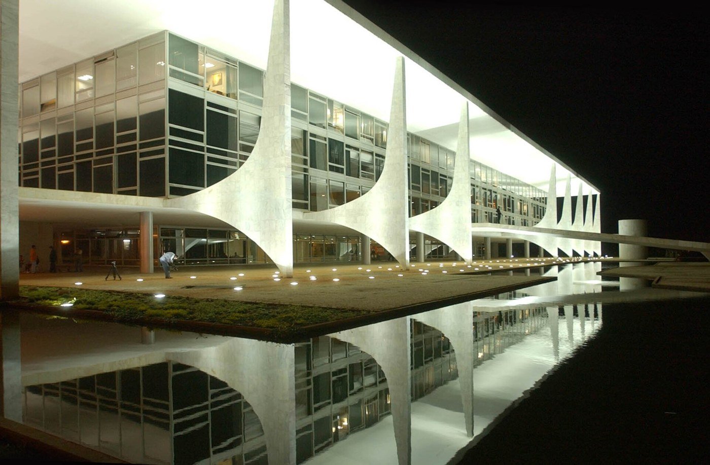 The Planalto Palace, the presidential office in Brasilia, lit at night with its curved white columns reflected in a pool