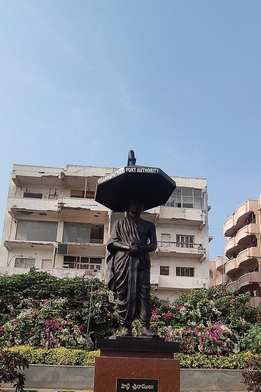 Bronze statue of Potti Sreeramulu holding an umbrella on a lawn at RK Beach, Visakhapatnam