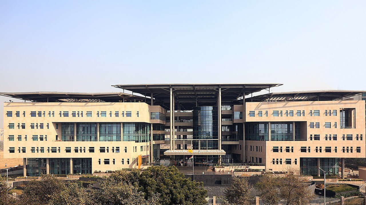 The wide sandstone-coloured Punjab National Bank head office building with a central glass atrium in Dwarka, Delhi