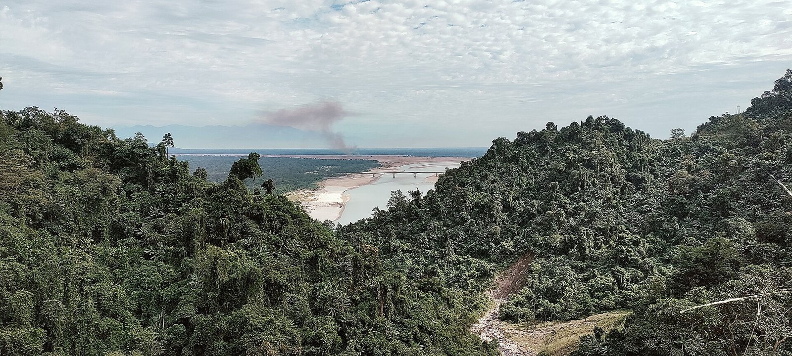 Wide view of the Siang river with a bridge and sandbanks where it leaves forested hills near Pasighat