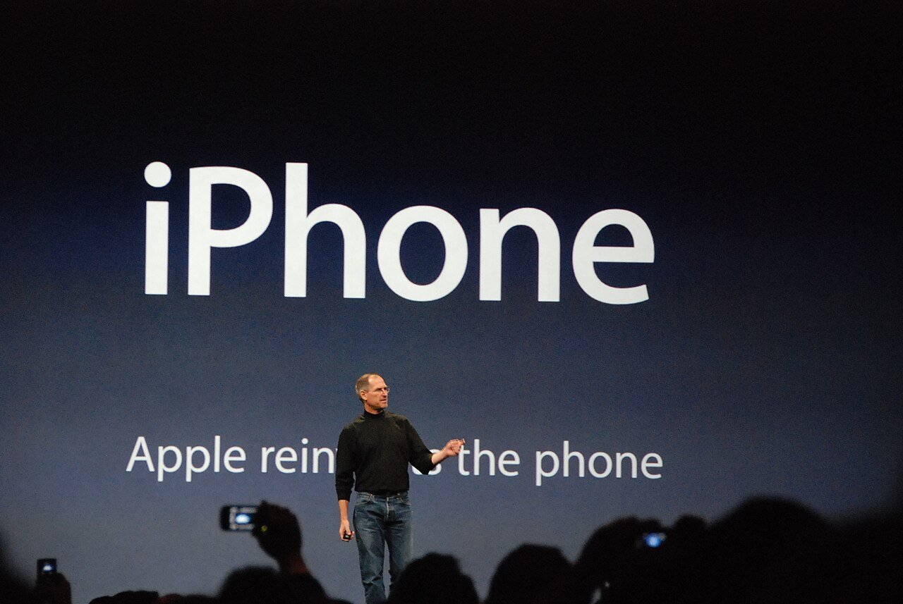 Steve Jobs on stage at Macworld San Francisco on 9 January 2007, with the line ‘Apple reinvents the phone’ behind him