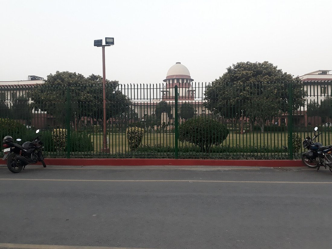 The domed Supreme Court of India building behind a green railing in New Delhi