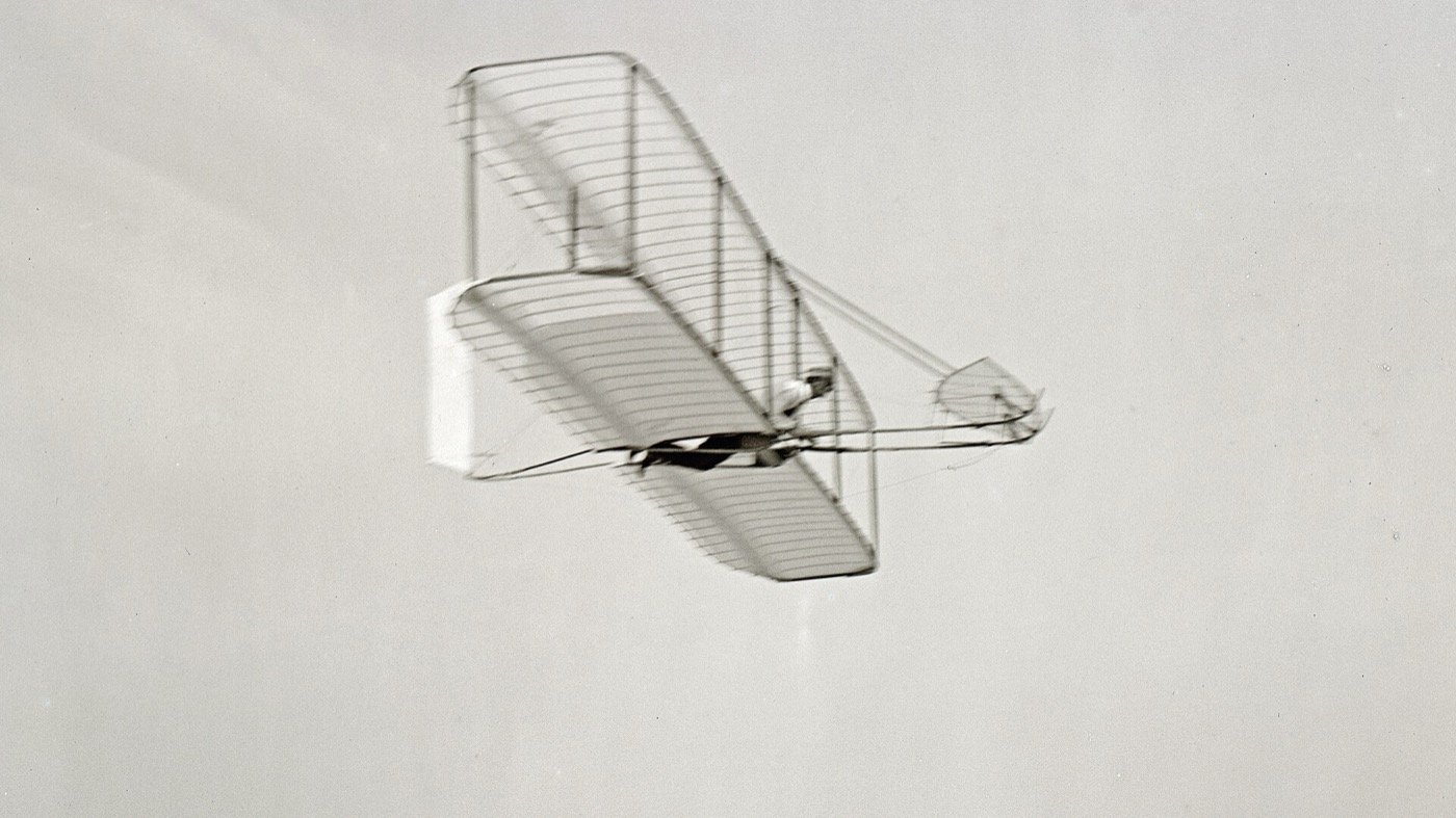 Wilbur Wright piloting the 1902 Wright glider in flight over the dunes near Kitty Hawk