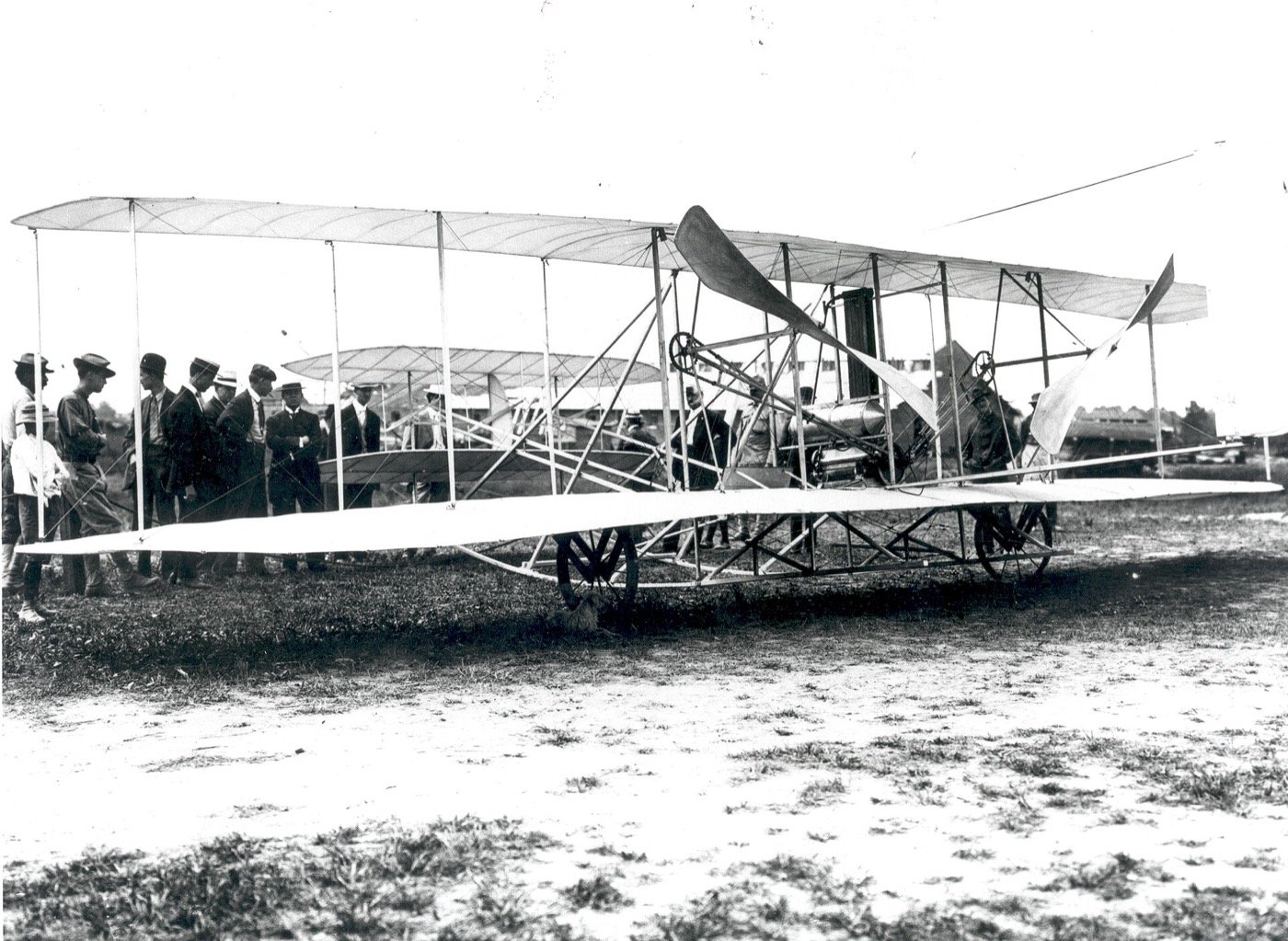 The Wright Flyer on the grass at Fort Myer with onlookers beside the wing